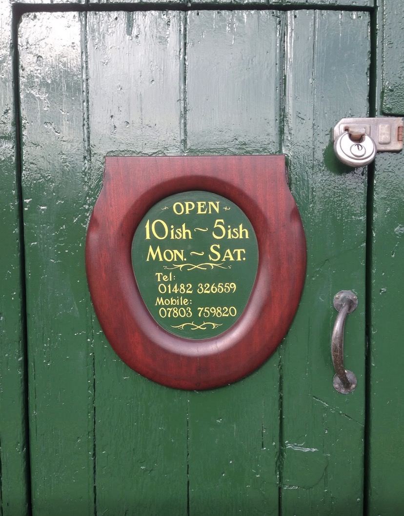 The hand-painted opening times sign on the green warehouse door